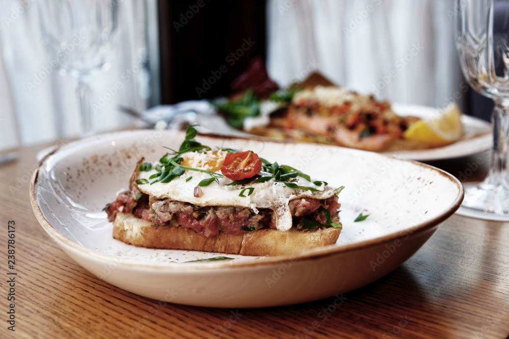 Sandwich with beef tartar and fried egg, toned image