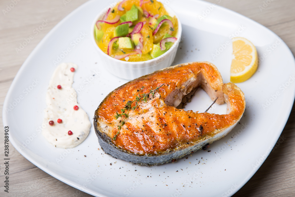 Grilled salmon, salad with oranges and avocado. Close-up, selective focus. Grilled salmon, salad with oranges and avocado. Close-up, selective focus.