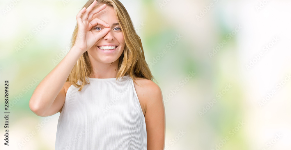 Beautiful young elegant woman over isolated background doing ok gesture with hand smiling, eye looking through fingers with happy face. Beautiful young elegant woman over isolated background doing ok gesture with hand smiling, eye looking through fingers with happy face.