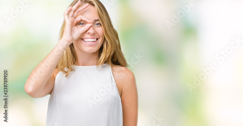Fototapeta Naklejka Na Ścianę i Meble -  Beautiful young elegant woman over isolated background doing ok gesture with hand smiling, eye looking through fingers with happy face.