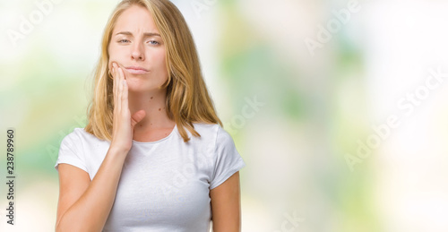 Beautiful young woman wearing casual white t-shirt over isolated background touching mouth with hand with painful expression because of toothache or dental illness on teeth. Dentist concept. © Krakenimages.com
