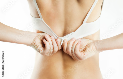 woman buttoning unfastening a white bra on a white background isolated