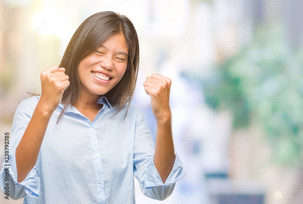 Young asian business woman over isolated background very happy and excited doing winner gesture with arms raised, smiling and screaming for success. Celebration concept.