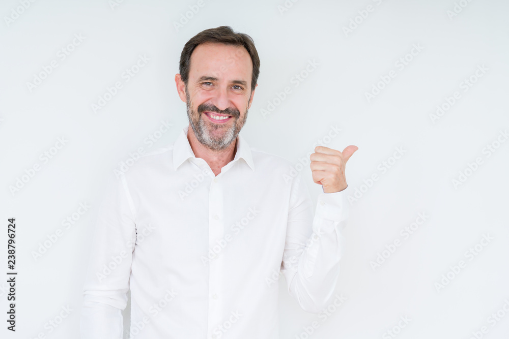 Elegant senior man over isolated background smiling with happy face looking and pointing to the side with thumb up. Elegant senior man over isolated background smiling with happy face looking and pointing to the side with thumb up.