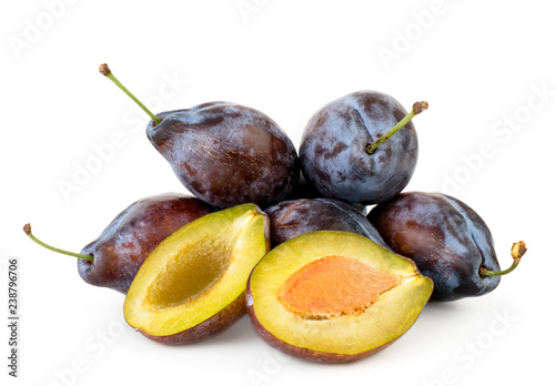 Heap of ripe plums and two halves close-up on a white background.