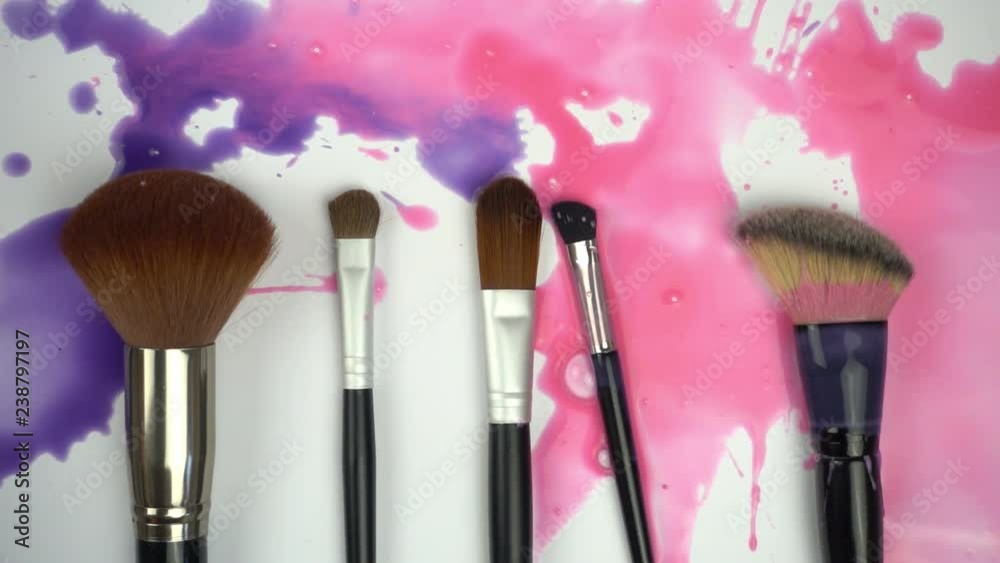 Splashes paints on makeup brushes in slow motion