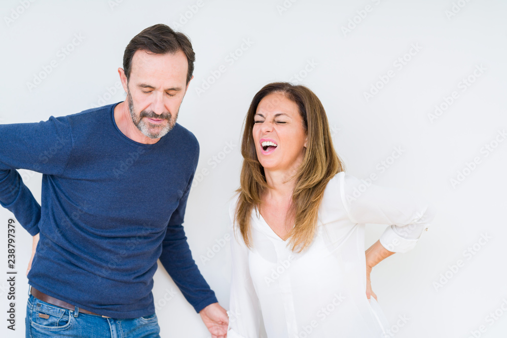 Beautiful middle age couple in love over isolated background Suffering of backache, touching back with hand, muscular pain Beautiful middle age couple in love over isolated background Suffering of backache, touching back with hand, muscular pain