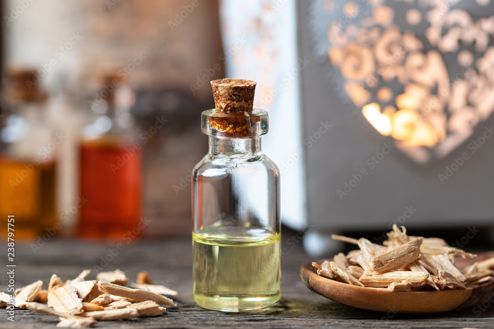 A bottle of cedar essential oil with pieces of cedar wood A bottle of cedar essential oil with pieces of cedar wood