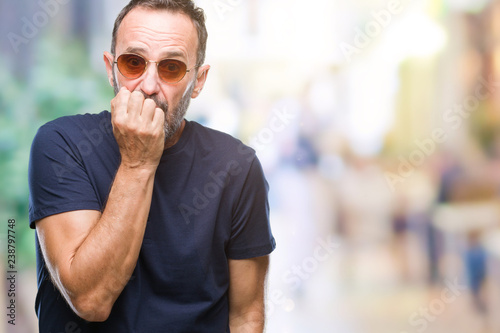 Middle age hoary senior man wearing sunglasses over isolated background looking stressed and nervous with hands on mouth biting nails. Anxiety problem.