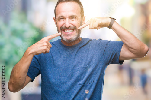 Middle age hoary senior man over isolated background smiling confident showing and pointing with fingers teeth and mouth. Health concept.