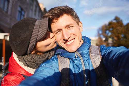 enamoured couple hugging, kissing and making selfie during the city walk photo