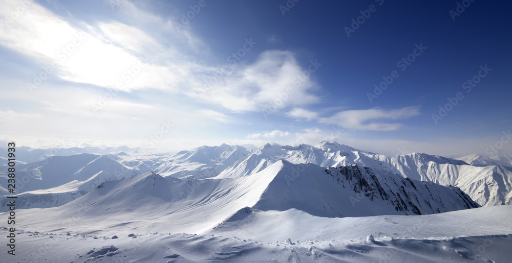 Panoramic view on snowy sunlight mountains at winter evening