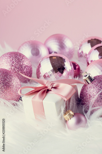 Pink Christmas decorations with gift box on white fur background, retro toned