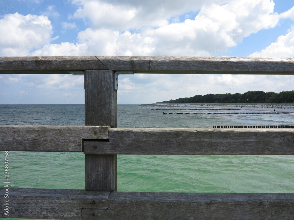 Blick durch ein altes hölzernes Geländer auf die Küste und das Meer Blick durch ein altes hölzernes Geländer auf die Küste und das Meer