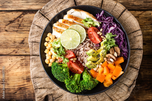фотографія Buddha bowl salad with chicken fillet, brown rice, avocado, pepper, tomato, broccoli, red cabbage, chickpea, fresh lettuce salad, pine nuts and walnuts