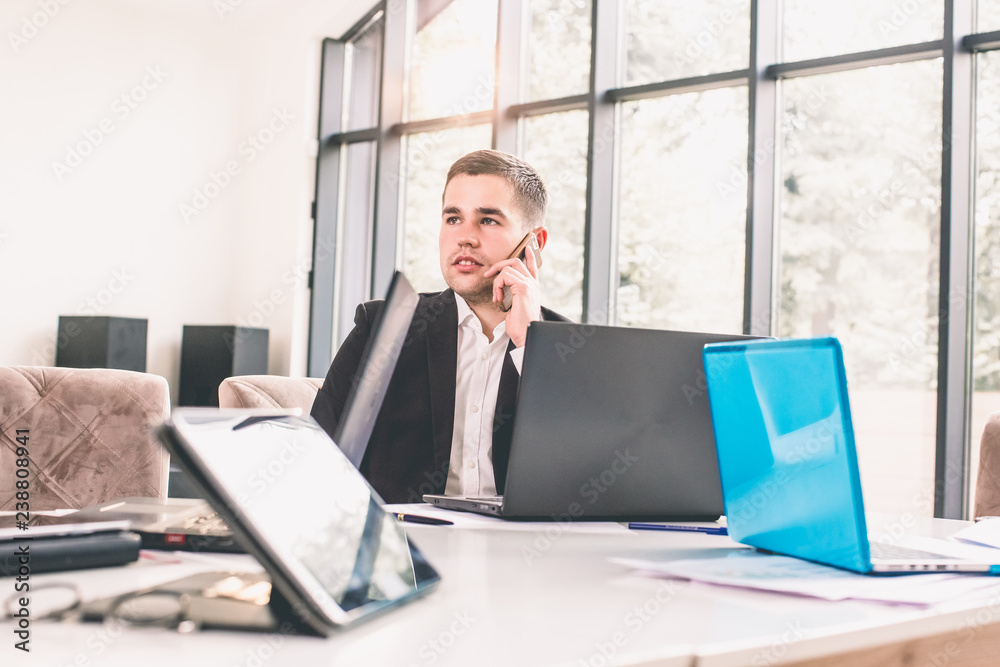 Handsome businessman in suit speaking on the phone in office