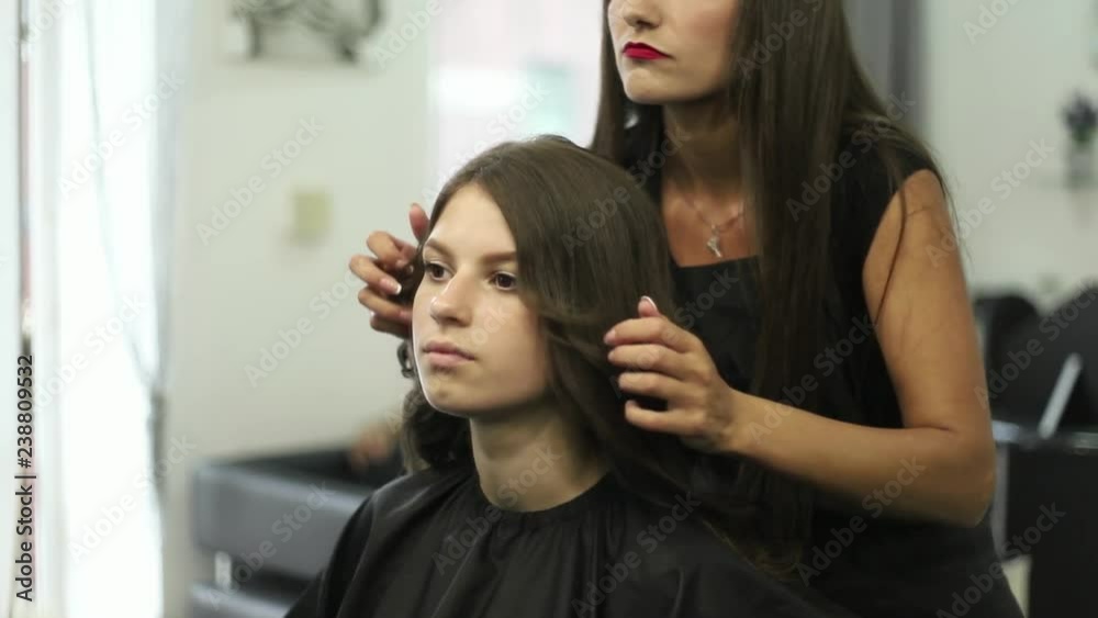 Young woman at the hair salon getting a haircut by female hairdresser Young woman at the hair salon getting a haircut by female hairdresser