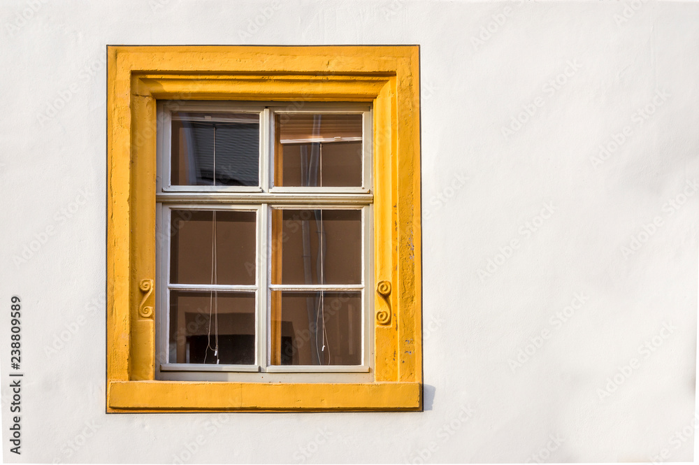 Fenster eines restaurierten Fachwerkhauses teils verputzt mit Sandsteinumrahmnung, verziert und gelber Fasche