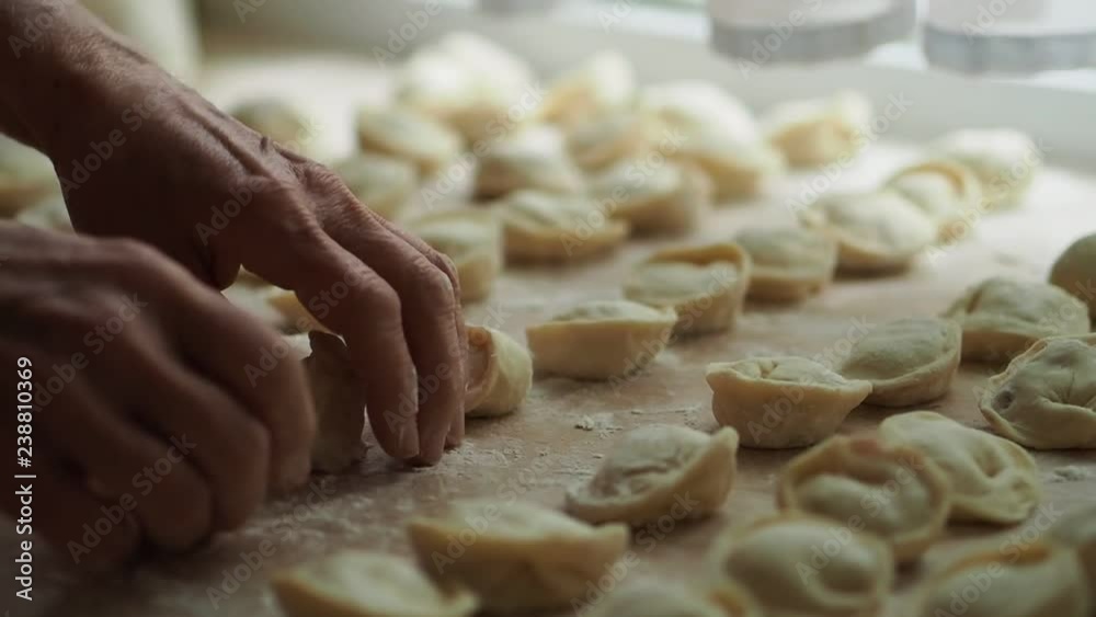 The old woman checks pelmeni. Semi-finished products lie on a table. Close up. The old woman checks pelmeni. Semi-finished products lie on a table. Close up.