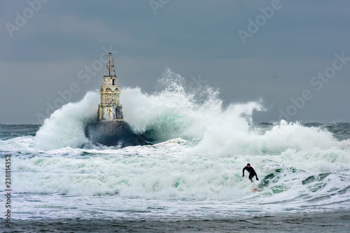 Storm at sea. Lighthouse and a surfer. 