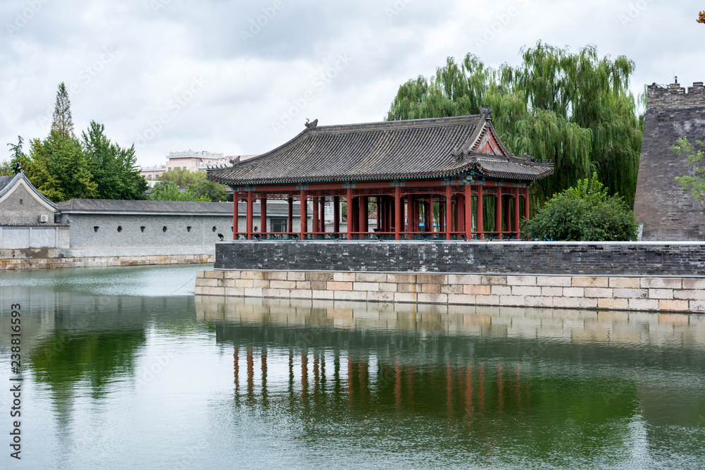 Pavilion on the north east corner of The Forbidden City, showing reflections in the surrounding tongzi river, Beijing, China.