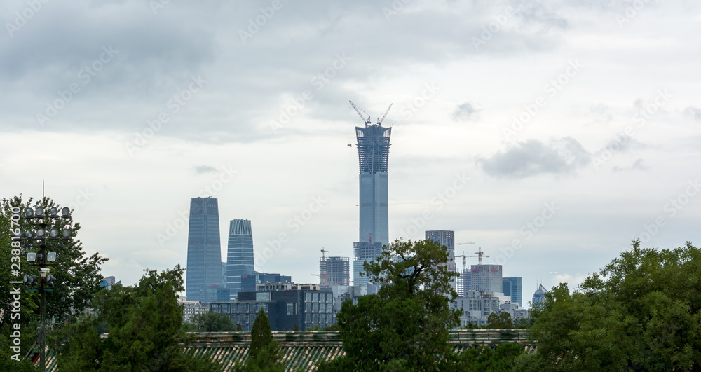 Downtown Beijing, seen over a chinese rooftop surrounded by trees