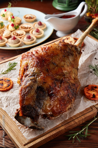Whole roasted lamb leg on wooden cutting board