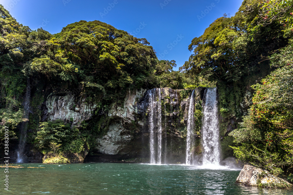 A waterfall in the island of Jeju in South Korea in a blue sky day