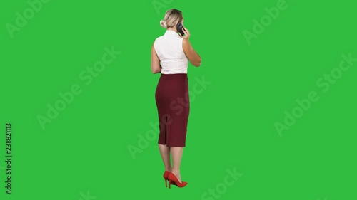 Standing young beautiful woman using a mobile phone making a call on a Green Screen, Chroma Key. photo