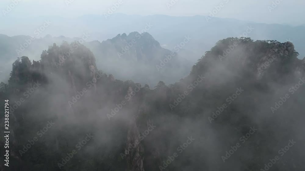 Tilting drone footage of breathtaking mountain landscape covered in fog and mist, spectacular view of Huangshan national park, on of China's most iconic landmark destinations