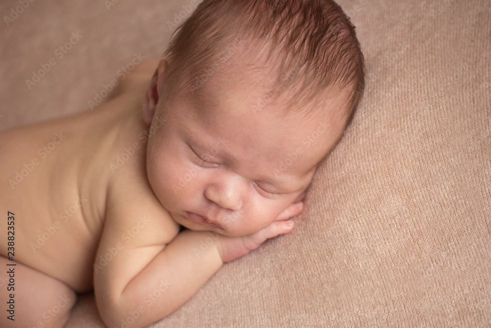 the first photo shoot. newborn child. newborn boy. the child lies on a beige blanket the first photo shoot. newborn child. newborn boy. the child lies on a beige blanket