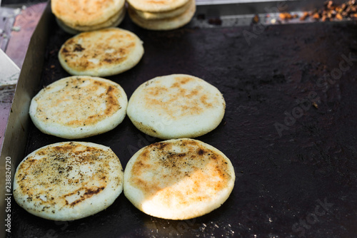 Close up photo of arepas, traditional Colombian corn patties filled with cheese, at a street food market