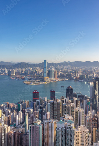 Vertical photo of the Hong Kong, China, skyline during sunrise as seen from Victoria Peak. Sky is  clear, no haze, boats can be seen on the water.