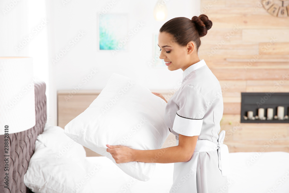 Young chambermaid making bed in hotel room Young chambermaid making bed in hotel room