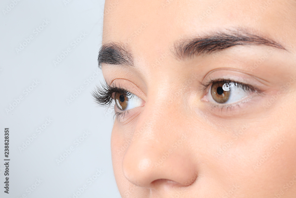 Fototapeta premium Young woman with beautiful eyelashes on gray background, closeup view
