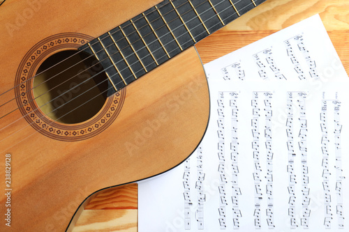 Beautiful classical guitar and music sheets on wooden background, top view