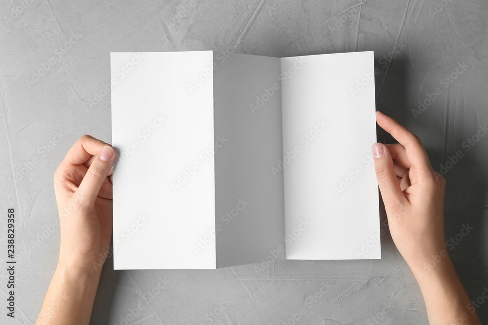 Woman holding blank brochure mock up on light background, top view Woman holding blank brochure mock up on light background, top view