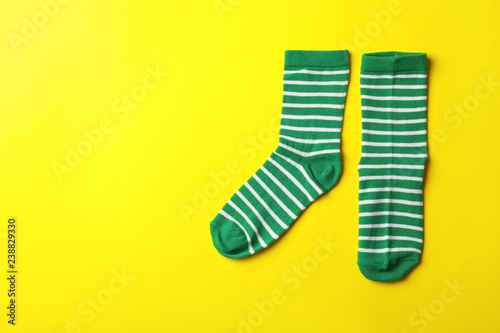 Pair of cute child socks and space for text on color background, top view