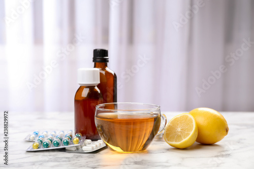 Cup of hot tea and different cough remedies on table