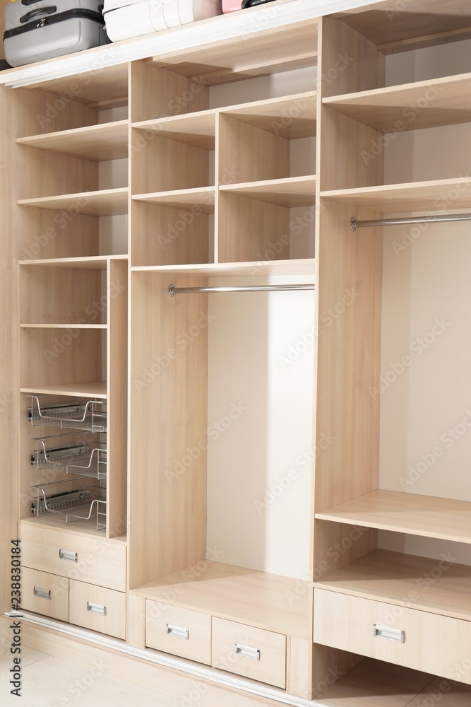 Empty wooden wardrobe with shelves and drawers in dressing room