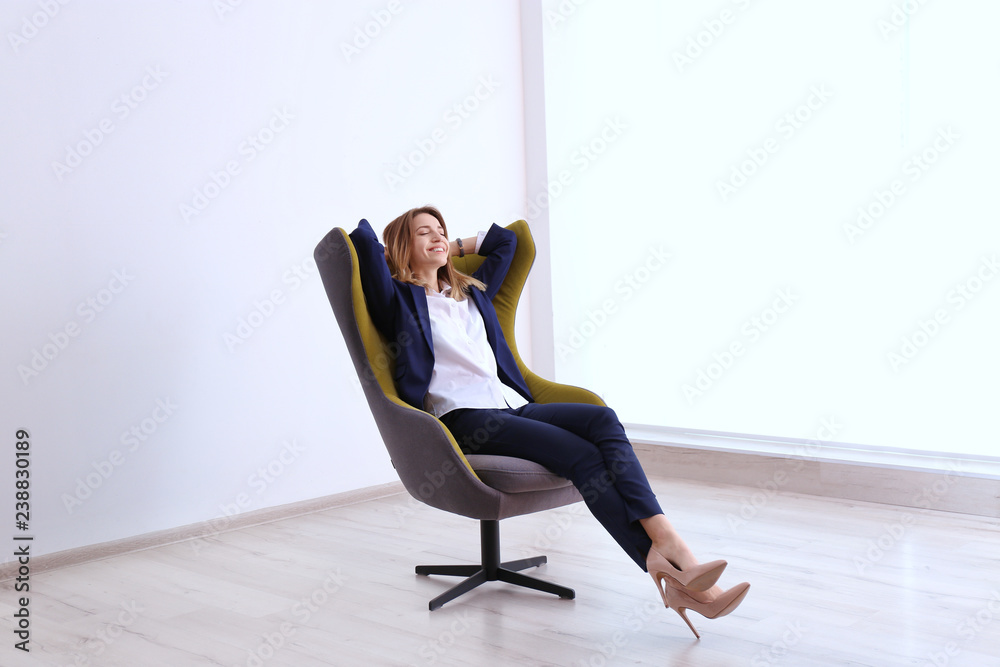 Fototapeta premium Young businesswoman sitting in comfortable armchair indoors
