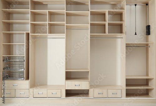 Foto Empty wooden wardrobe with shelves and drawers in dressing room