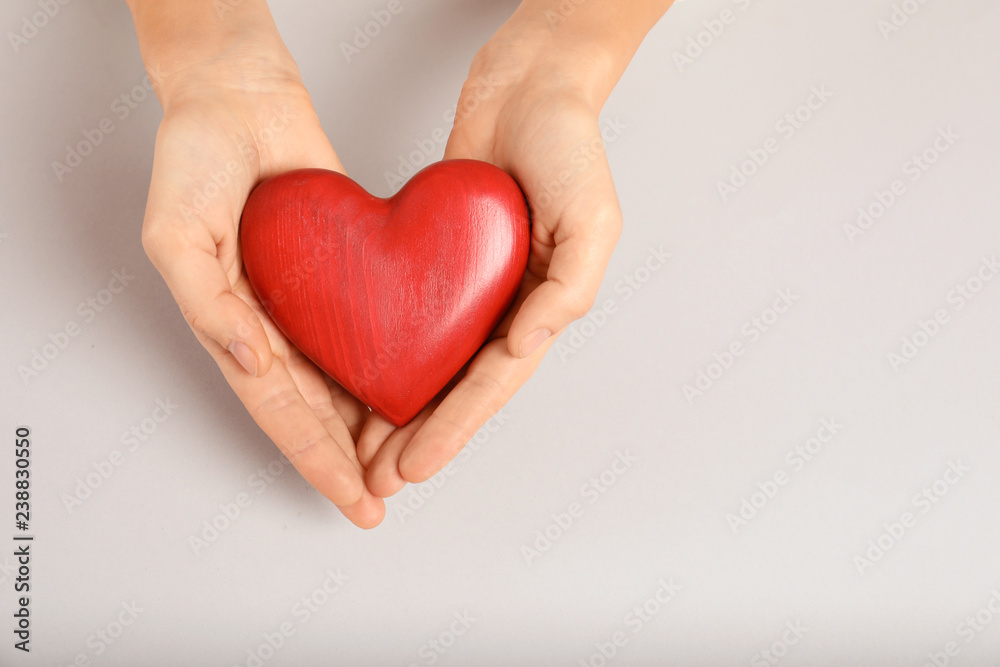 Woman holding decorative heart on light background, top view with space for text