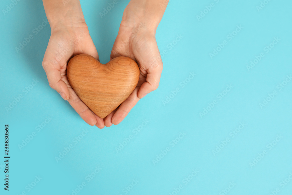 Obraz premium Woman holding decorative heart on color background, top view with space for text