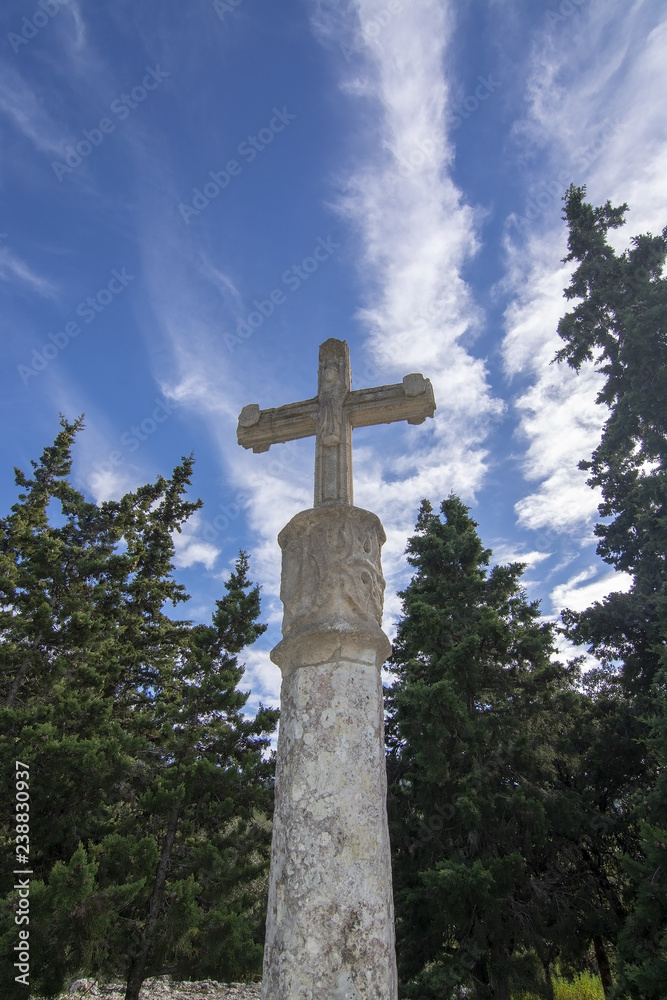 White stone cross standing in evergreen forest
