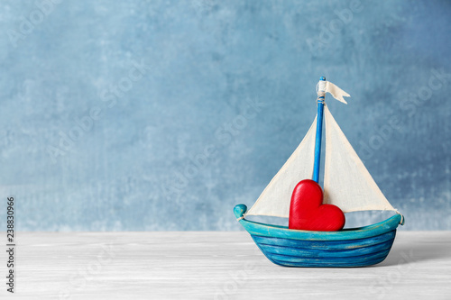 Toy ship with red decorative heart on table. Space for text