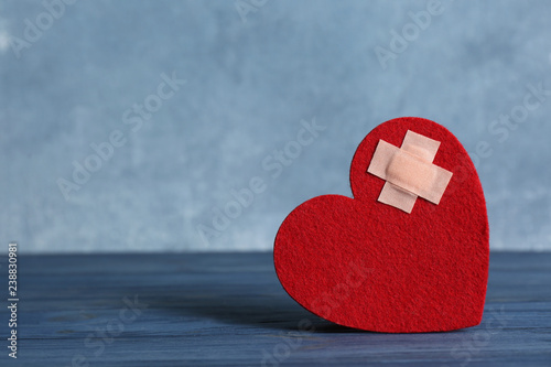 Φωτογραφία Red felt heart with adhesive plasters on table. Space for text