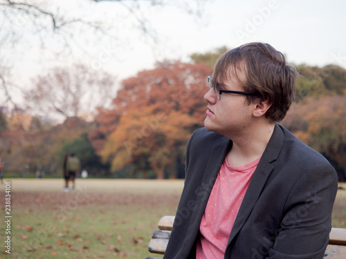 A young man sat on a park bench looking to  his right photo