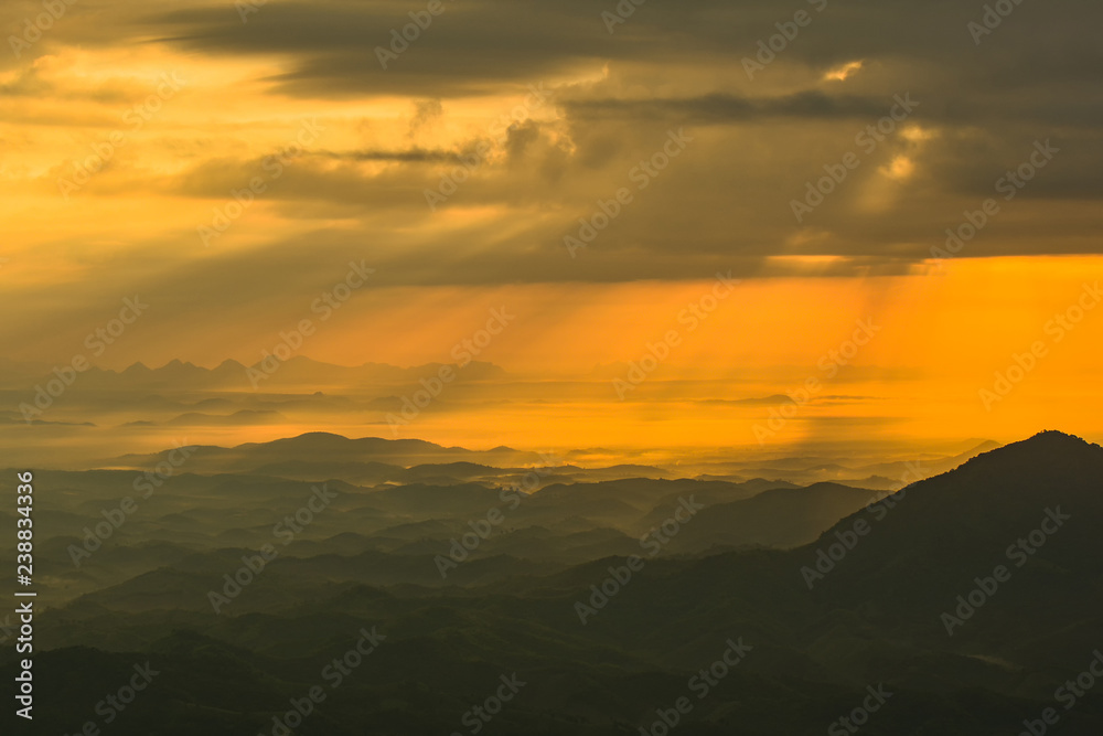 landscape sunrise on hill mountain with rays of sunlight shining on the cloud yellow sky