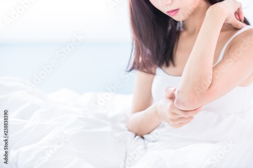 woman scratching arm and elbow